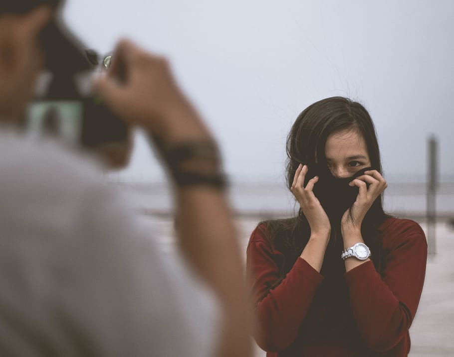 selective focus photography of person wearing white shirt taking photo of woman wearing red long-sleeved shirt covering her face with hair, HD wallpaper