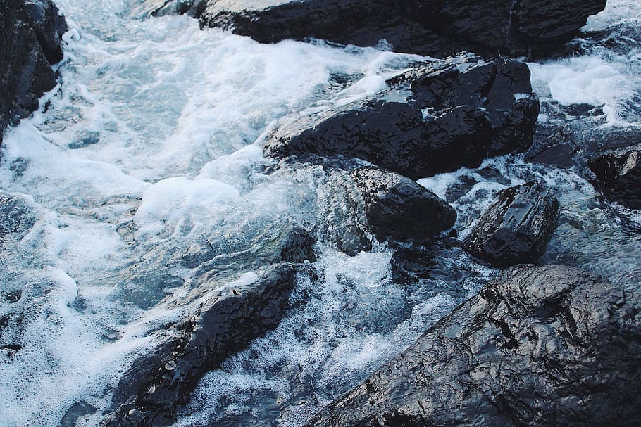 High Angle Photo of Body of Water Splashing Against Gray Rocks HD wallpaper