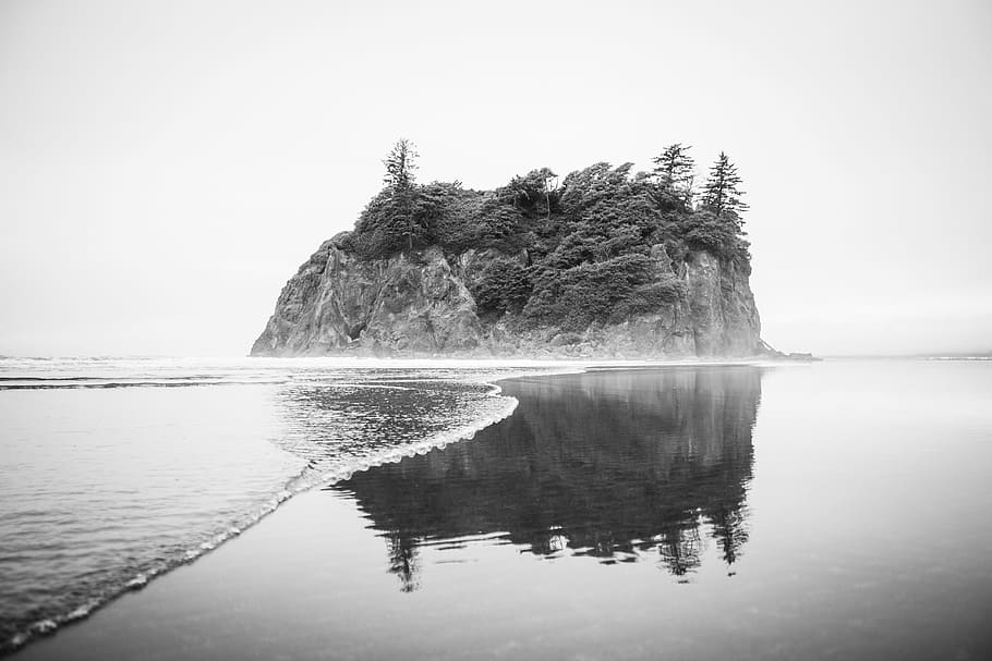 grayscale photo of island surrounded by water, beach, rock, wave