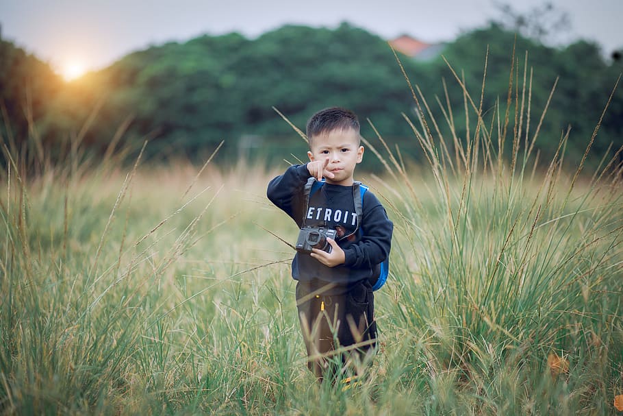 Boy Standing on Green Field Holding Black Camera, child, grass HD wallpaper