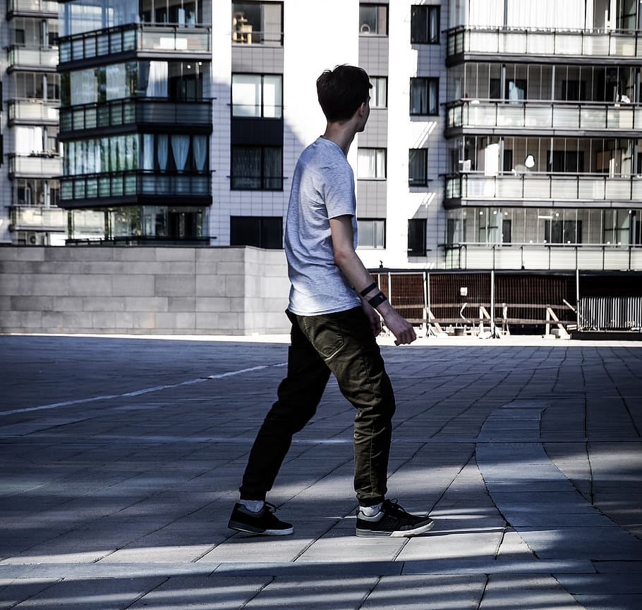 man walking on gray brick pavement near white building, person HD wallpaper