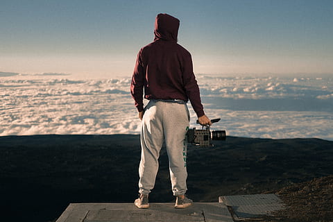 man holding video camera, videographer, stand, record, film, hoodie HD wallpaper