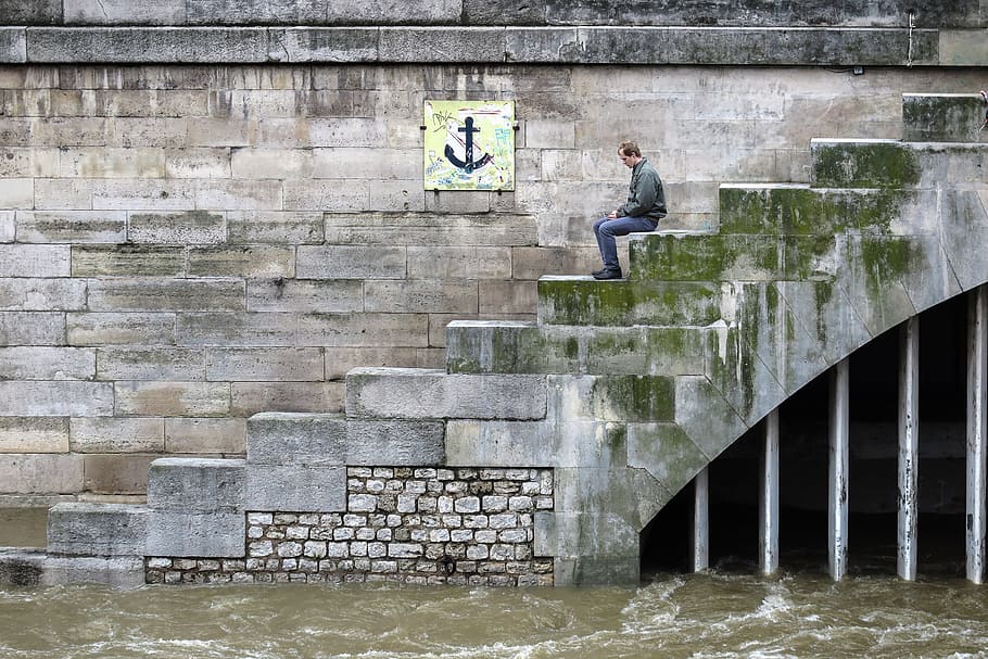 A man sits on steps leading to the flooded Seine river in Paris, France HD wallpaper