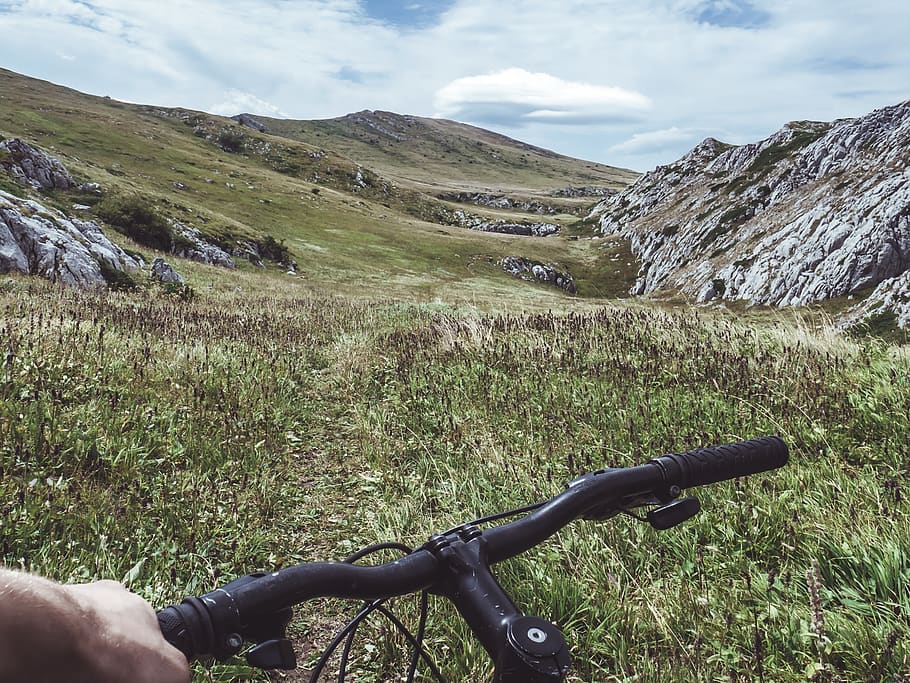 Person Riding Bicycle Overlooking Green Grass Field and Hill HD wallpaper