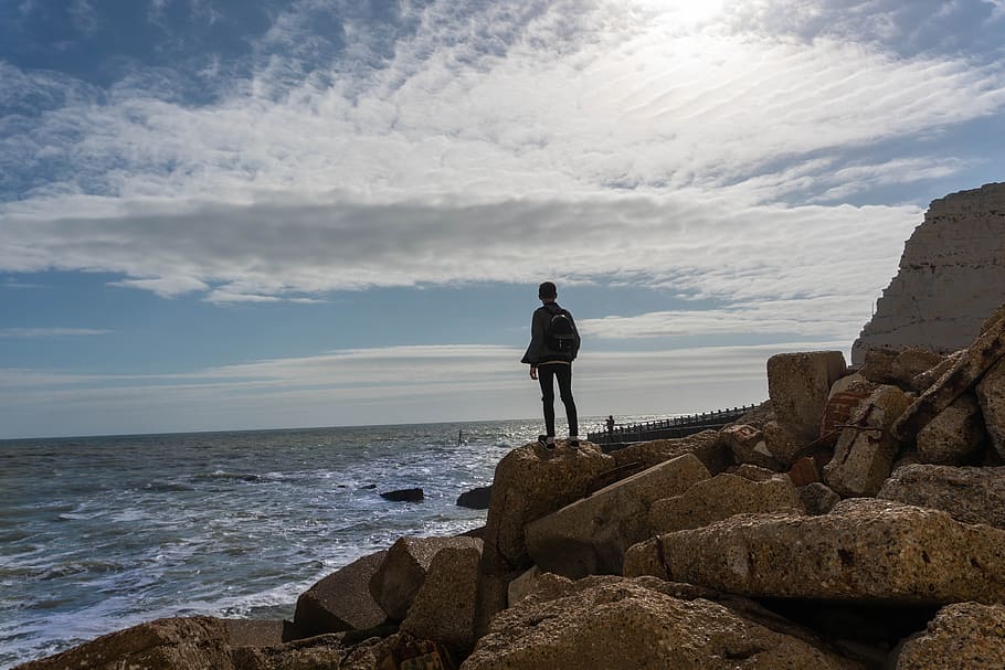 Person Standing on Rock in Front of Sea, alone, blue sky, cloudy sky HD wallpaper