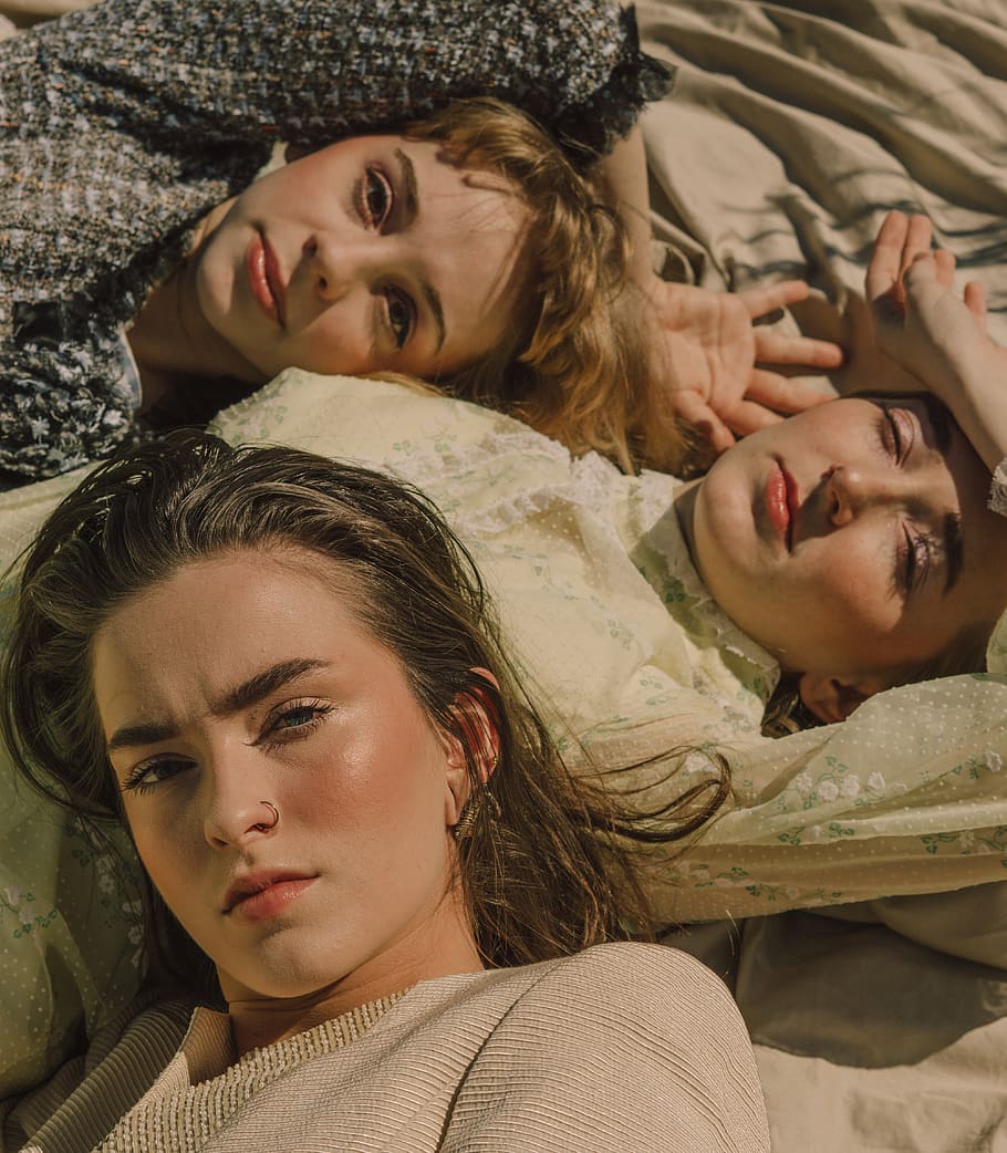 three women lying on white surface, portrait, looking at camera HD wallpaper