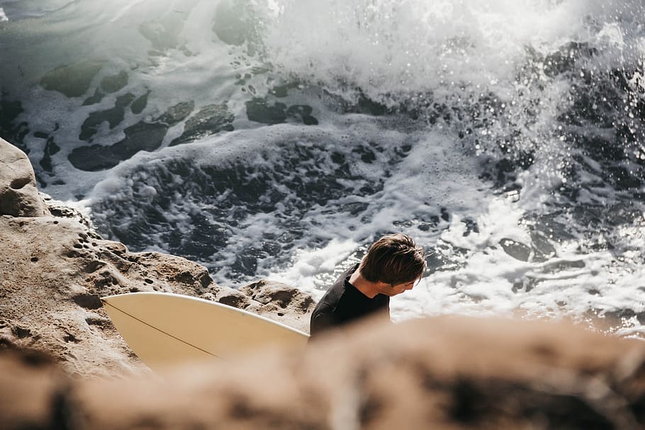 man holding surfboard beside sea, surfer, surfing, male, wafe HD wallpaper