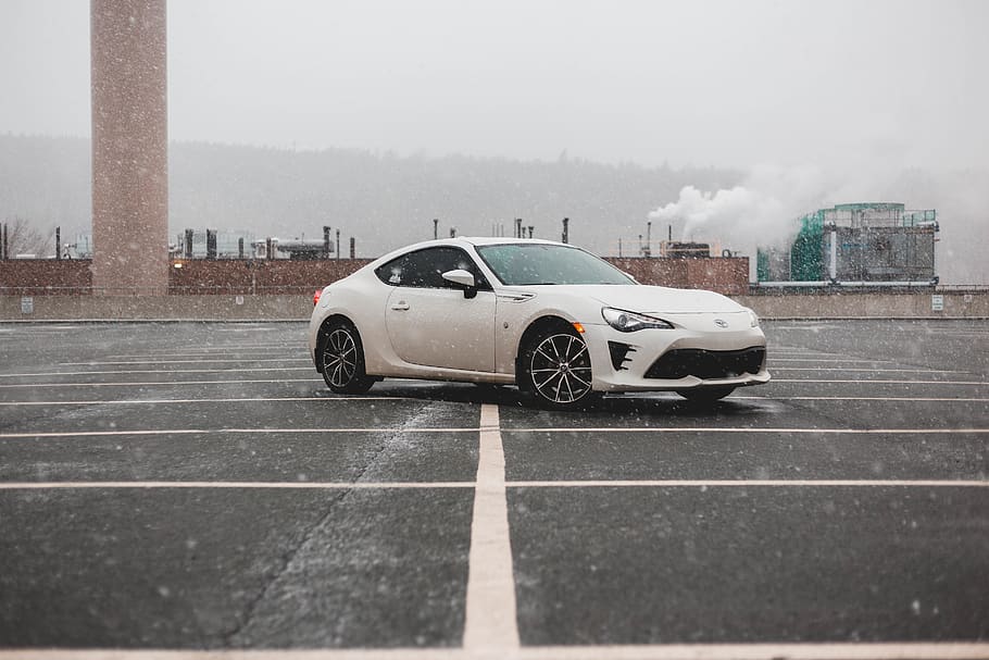 white Toyota GT86 coupe parked on pavement during snowy weather