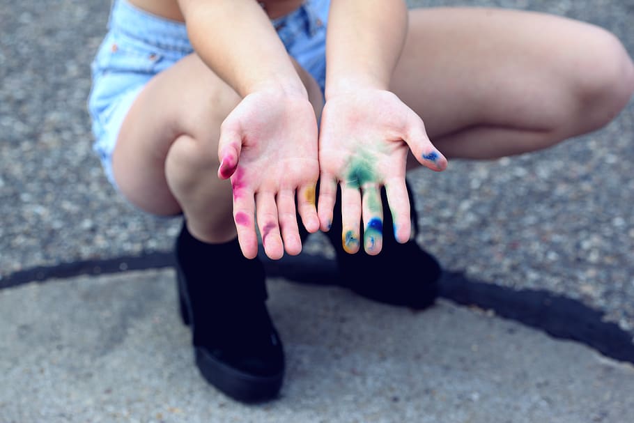 Woman Squatting Holding Out Her Hands With Assorted Paints, body