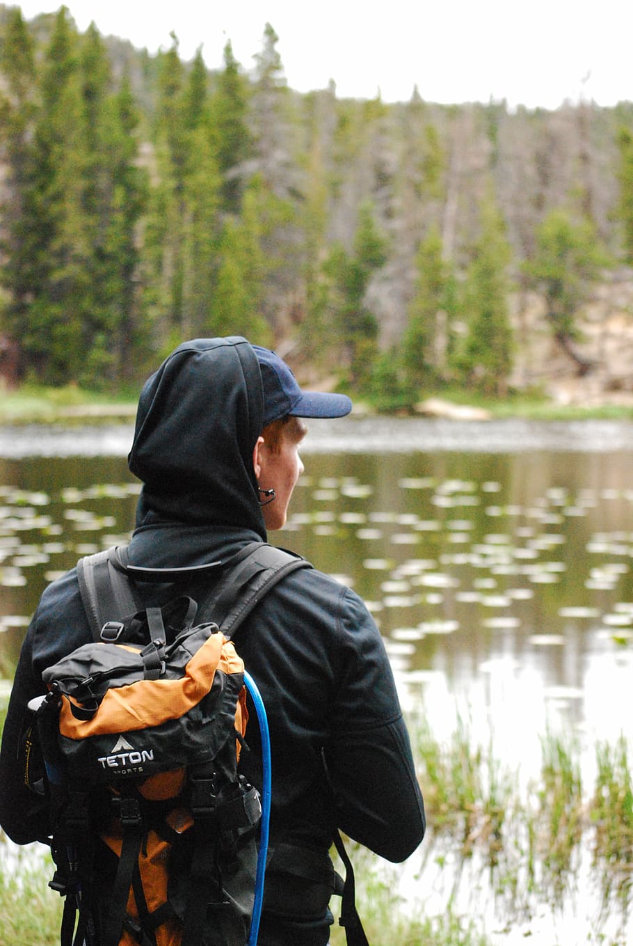 person wearing black jacket and orange and black backpack, human
