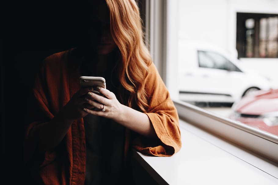 woman leaning beside window while using iPhone, smartphone, window light HD wallpaper