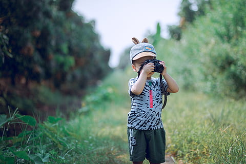 Boy Using Camera Near Green Leaf Plants, blurred background, cap HD wallpaper