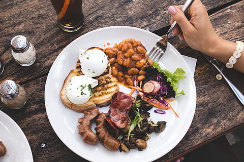Eating high protein brunch with poached eggs, beans and bacon HD wallpaper