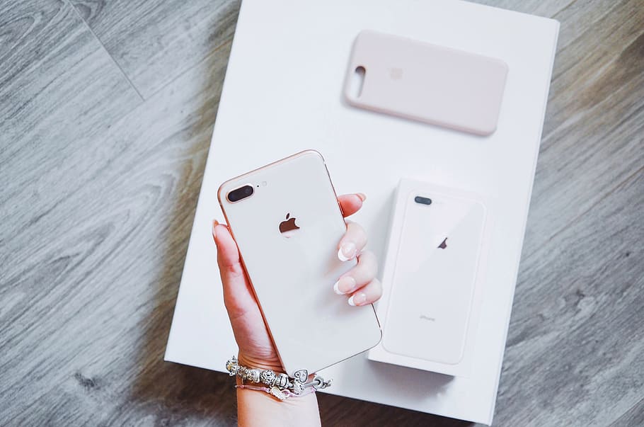 person holding gold iPhone 8 Plus near box and case, united kingdom