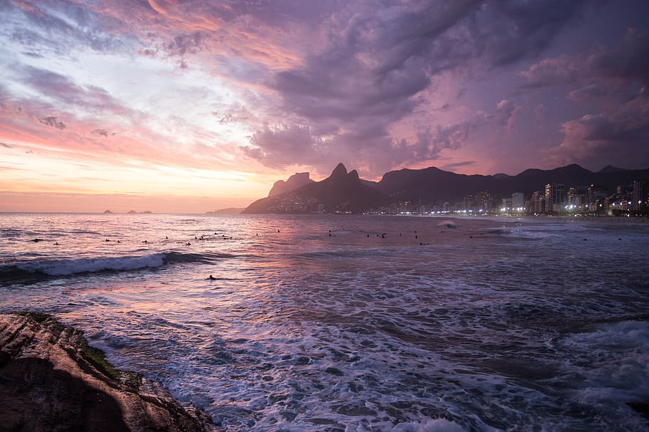 white buildings beside seashore behind mountain under thick clouds HD wallpaper