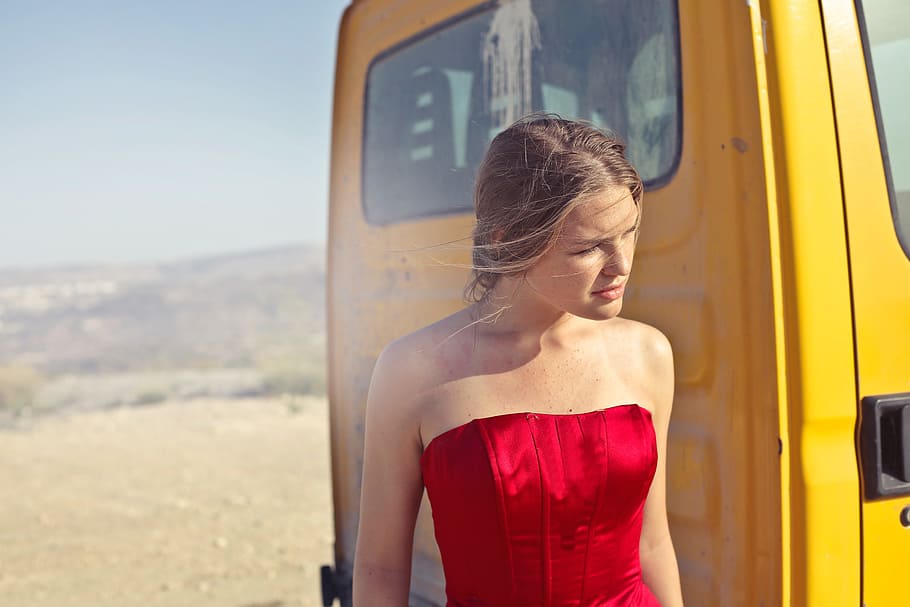 Young Adult Woman In Red Party Gown Dress Standing Near Yellow Truck During Outdoor Photoshoot, HD wallpaper
