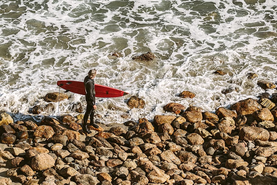 Man Wearing Wetsuit and Holding Red Surfboard on Shore, beach HD wallpaper