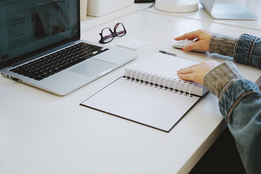 person touching white spiral notebook, laptop, computer, table HD wallpaper