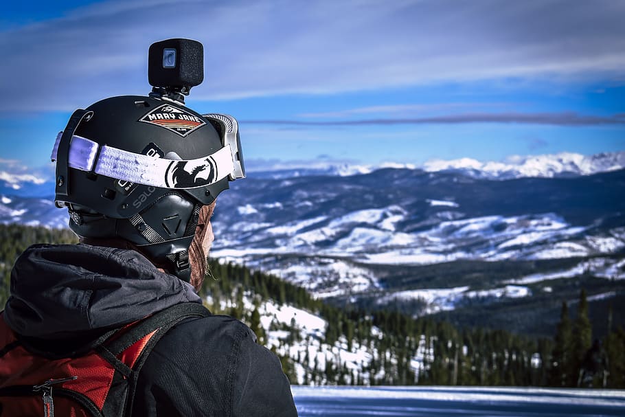 Man in Helmet With Action Camera Looking at Snow Mountain, clouds HD wallpaper