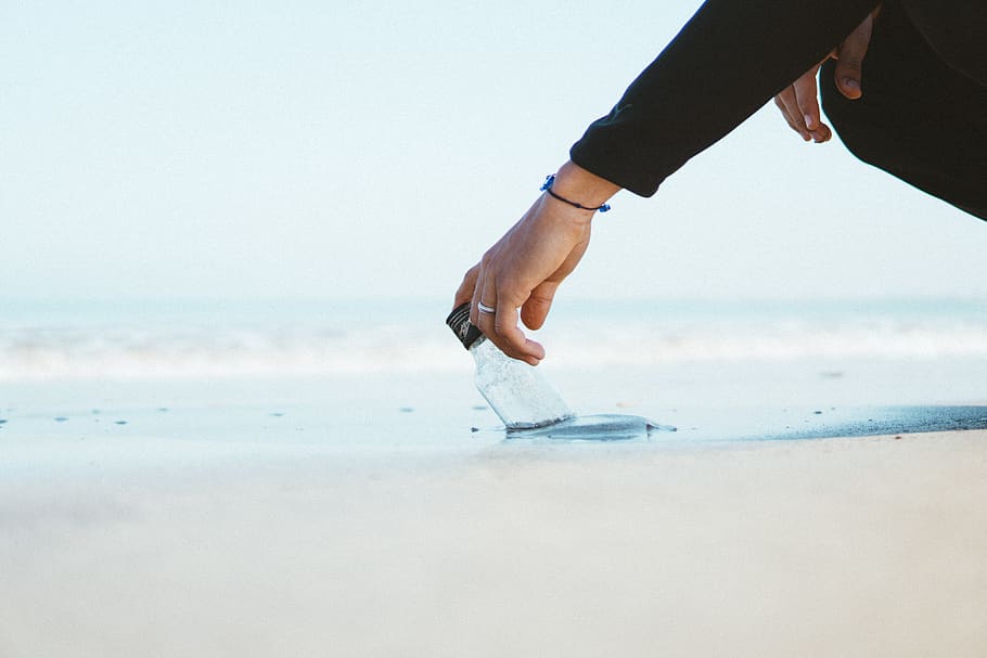Person Wearing Black Long-sleeved Top Holding Bottle in Ocean HD wallpaper