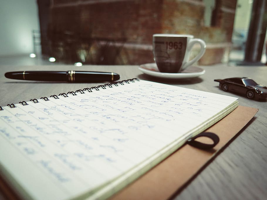Closeup Photo of Blue Pen Tinted Spiral Notepad Placed Beside Pen Die Cast Car and Coffee Cup HD wallpaper