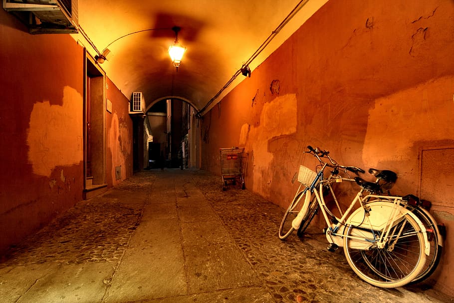Two bicycles parked against the wall during night time, bike
