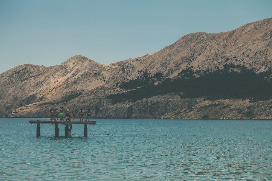 People Standing on Terrace in Middle of Body of Water Within Mountain Range HD wallpaper