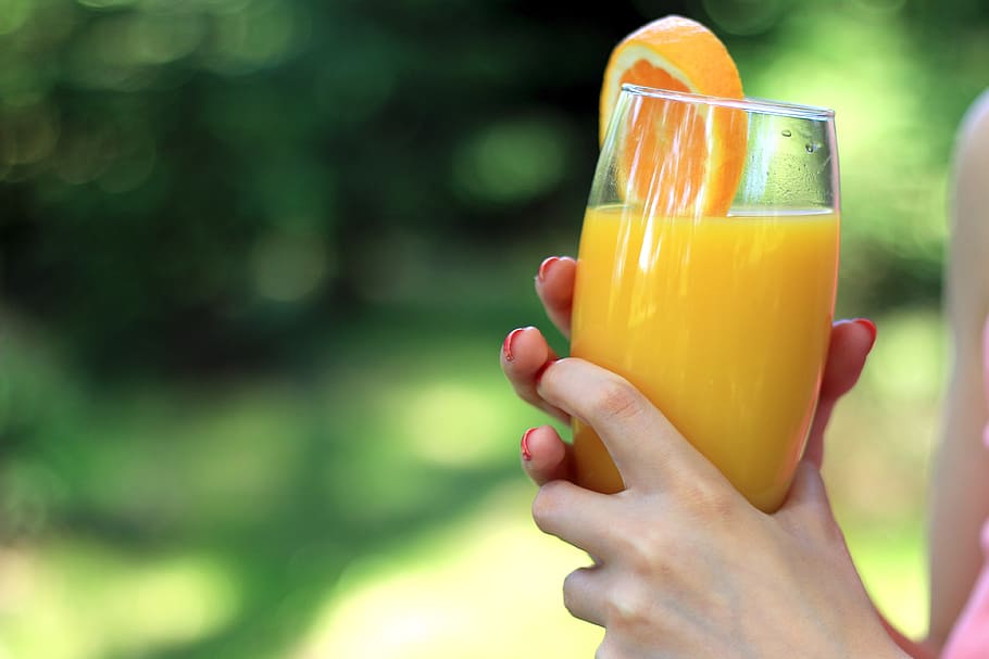 Glass of orange juice in the hands of woman in nature, human hand HD wallpaper