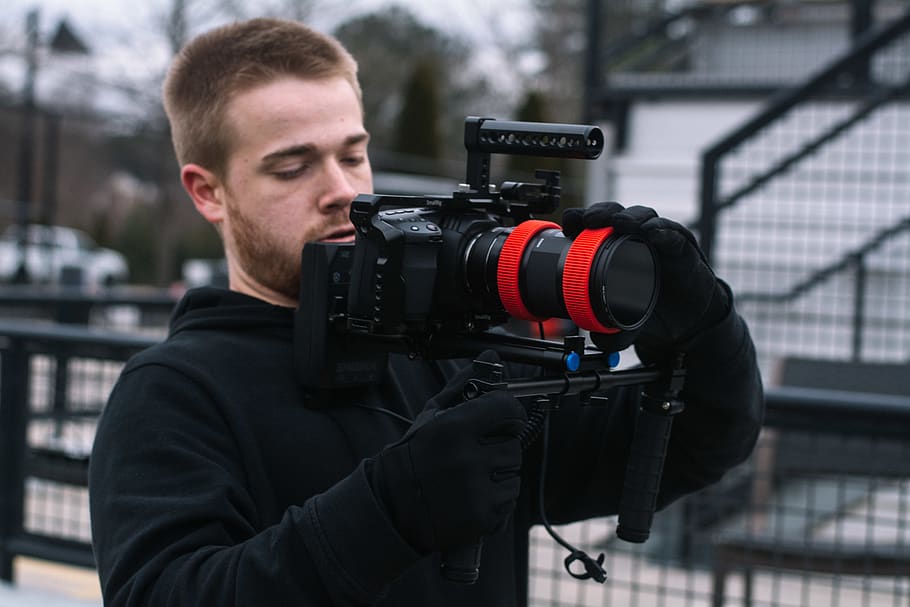 man wearing black pullover hoodie and black gloves holding black DSLR camera with stabilizer, HD wallpaper