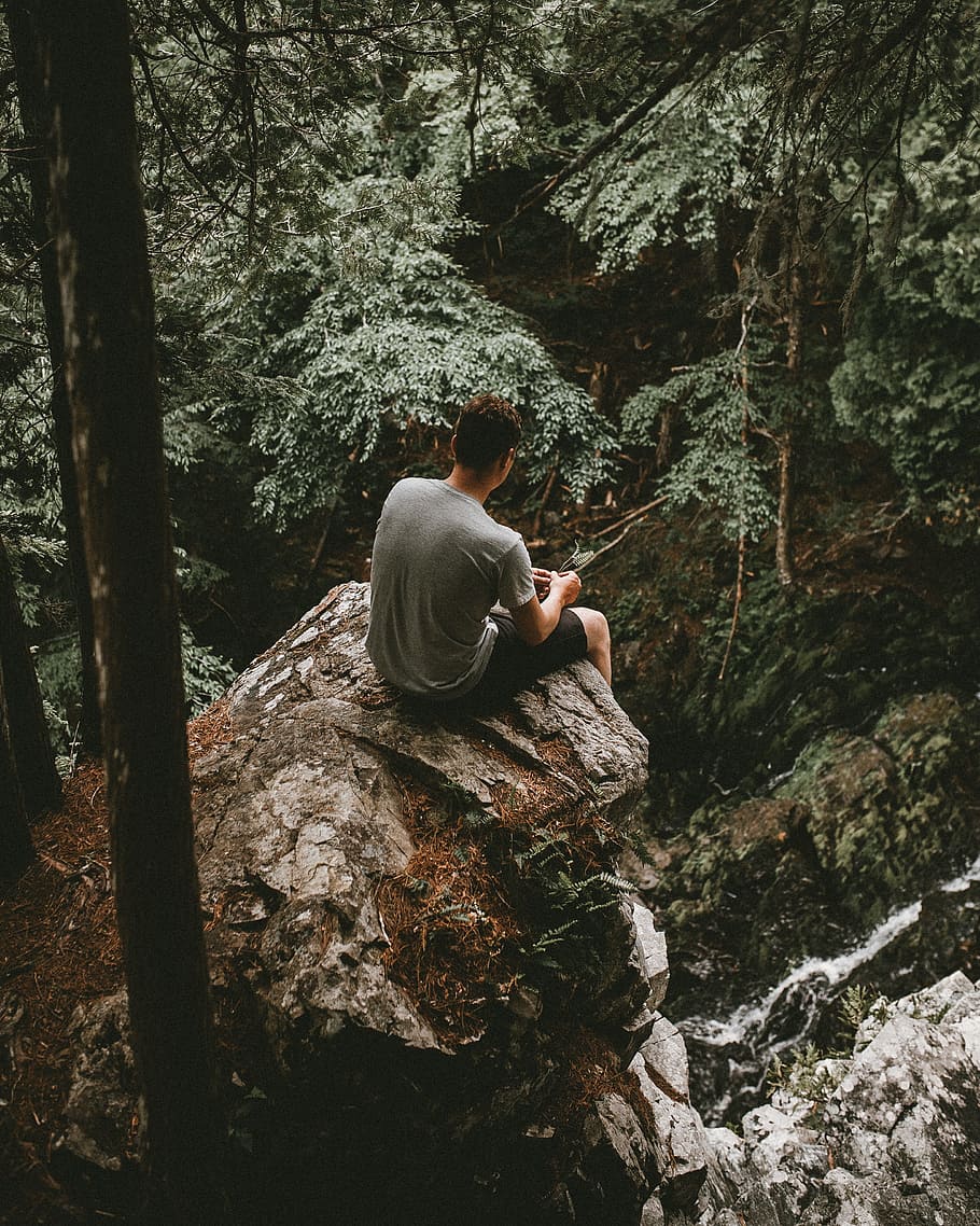 man sitting on gray rock near the cliff at daytime, person, tree HD wallpaper