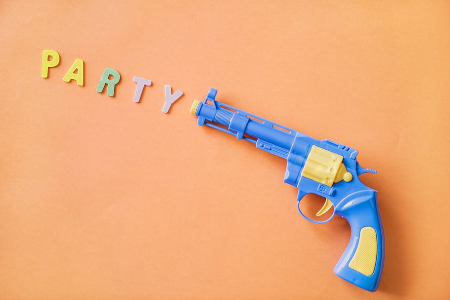 Blue and Yellow Plastic Revolver Toy With Party Sign, background