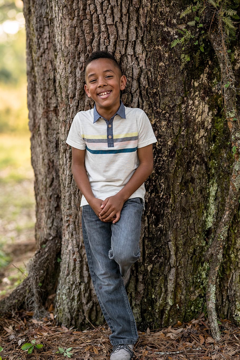 smiling boy leaning on tree during daytime, one person, tree trunk HD wallpaper