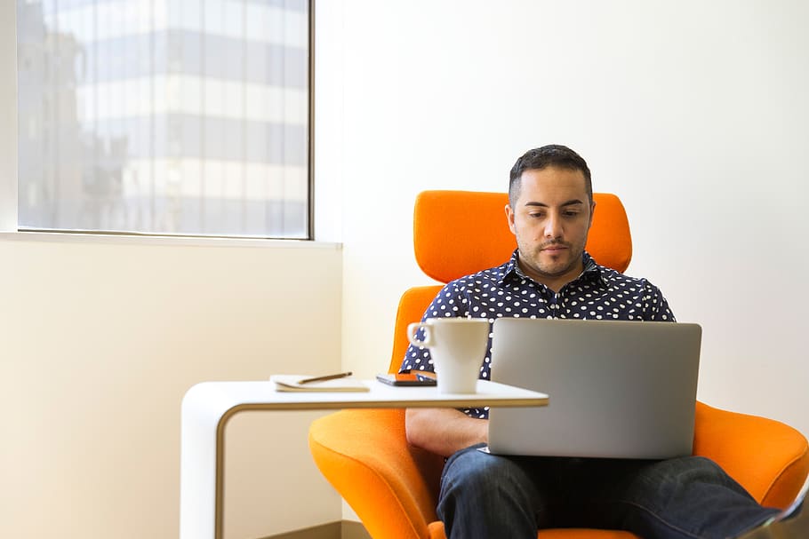 Man Sitting on Orange Sofa Chair With Gray Laptop Computer on His Lap, HD wallpaper