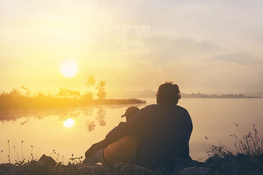 Two People On Grass Beside Body Of Water During Golden Hour, backlit HD wallpaper