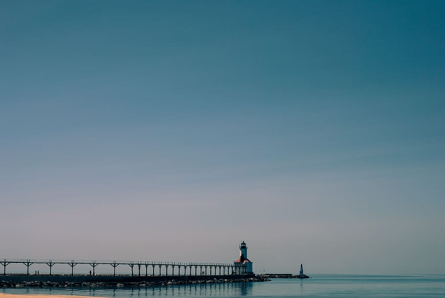 Dock Near White and Brown Concrete Lighthouse Surrounded by Calm Body of Water HD wallpaper
