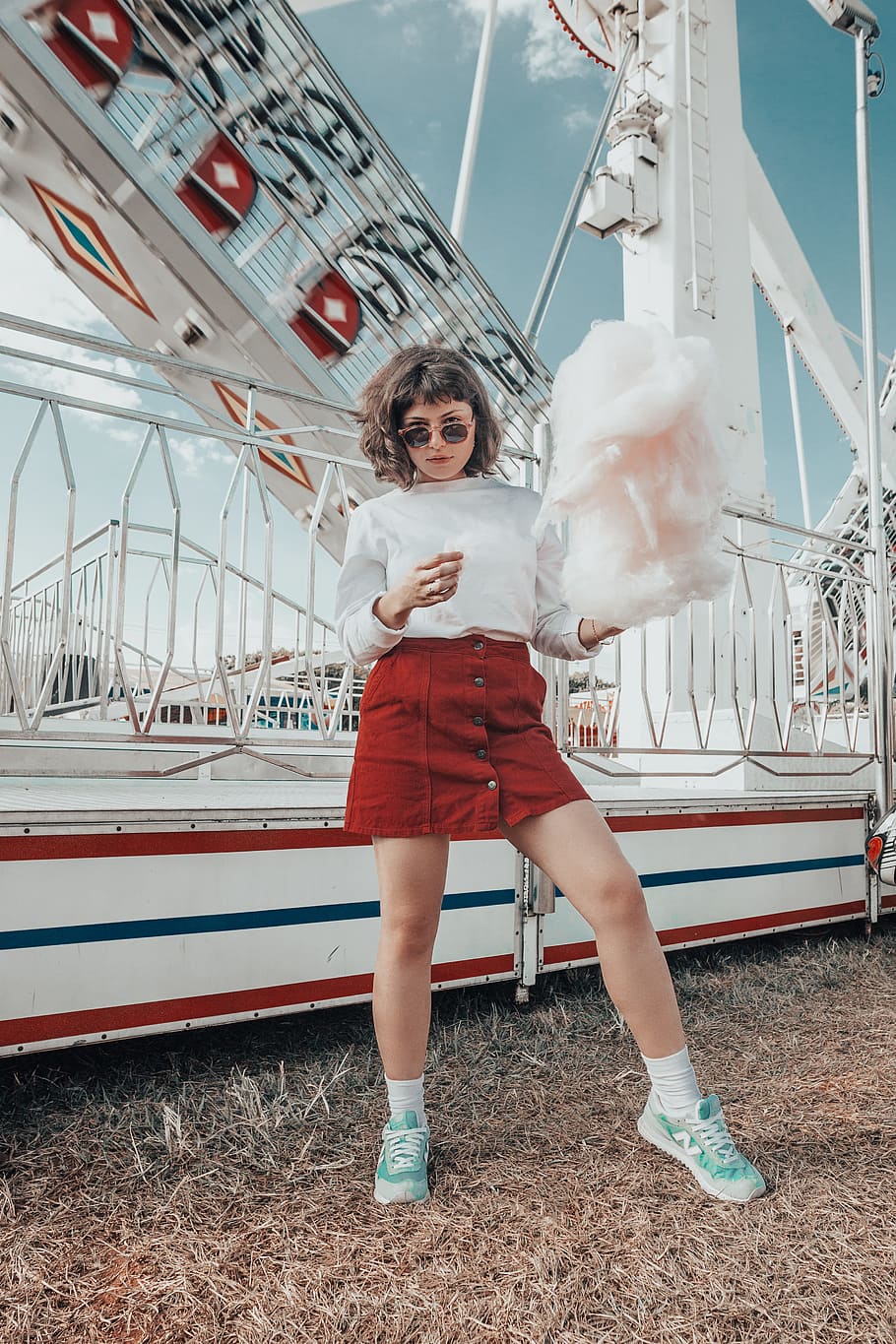 woman in white long-sleeved top holding cotton candy, floss, theme park