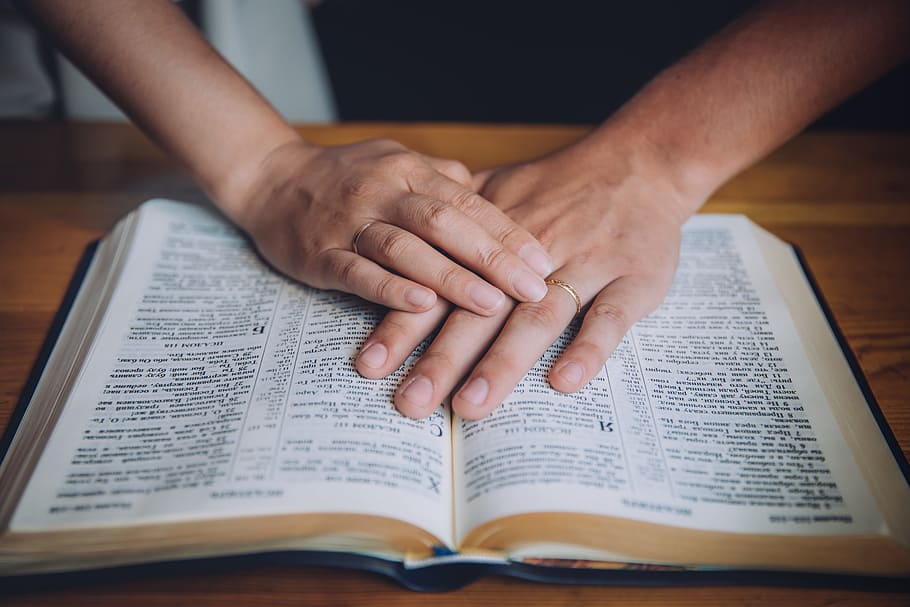 person holding opened book on brown table, bible, hand, pray