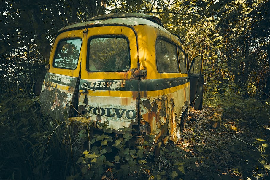 wrecked yellow Volvo minivan in forest, rust, transportation