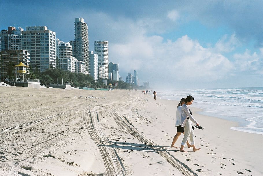people walking on seashore near concrete buildings during daytime, HD wallpaper