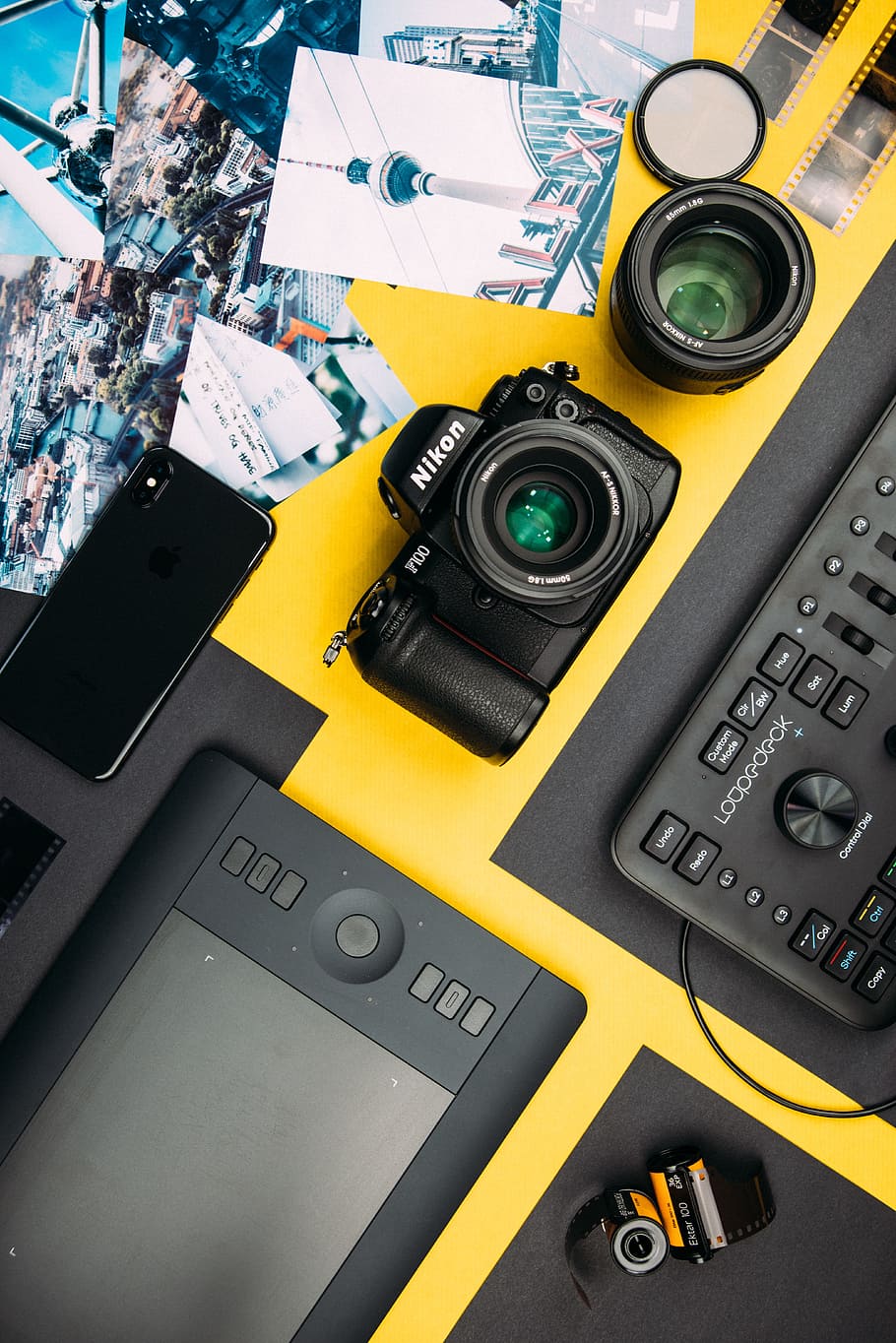 black Nikon DSLR camera beside space gray iPhone X, table, lens