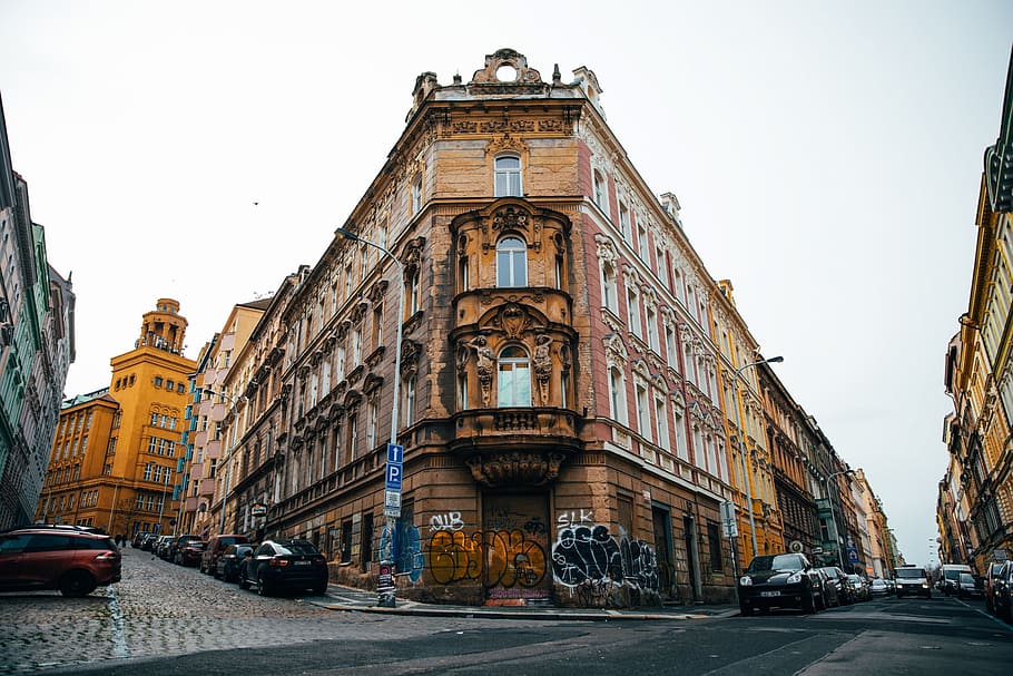 An old corner building in Prague with cars parked on the streets along both sides