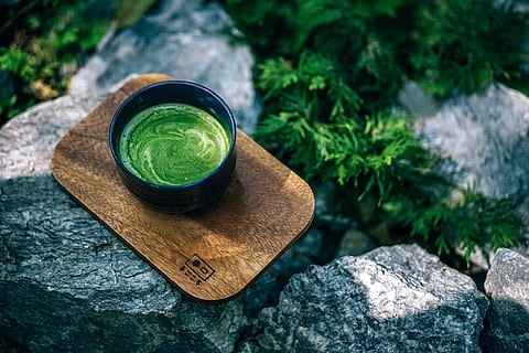 a large glass of matcha latte green tea and straw on a white marble board  against a backdrop of textured wall and plants in pots. Detox. 17567235  Stock Photo at Vecteezy