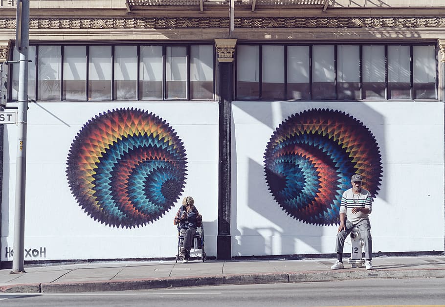 two men sitting near white wall painting during daytime, graffiti HD wallpaper