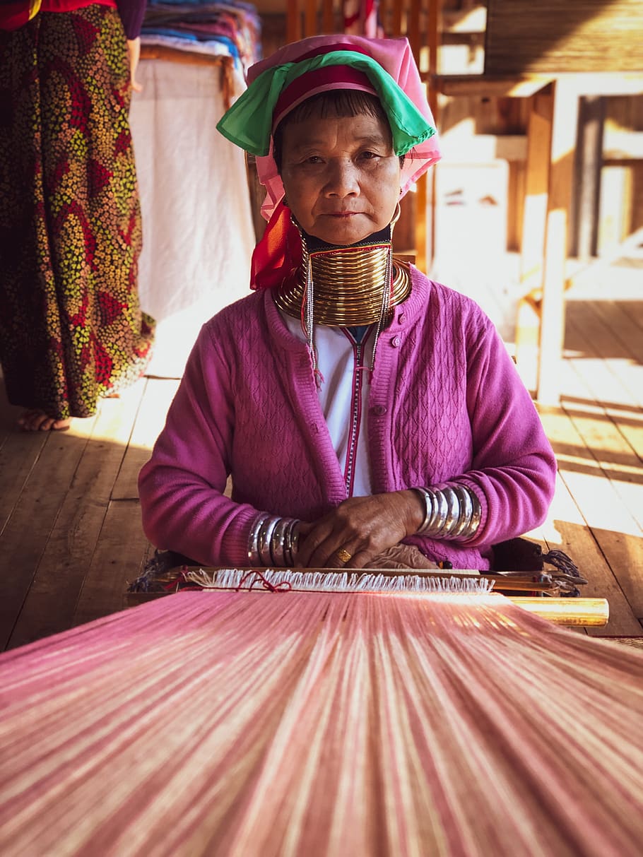selective focus photography of woman sitting beside woven textile