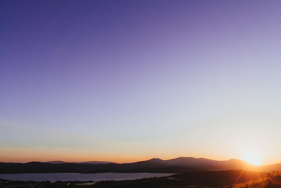 silhouette-of-mountains-near-body-of-water-during-orange-sunset.jpg