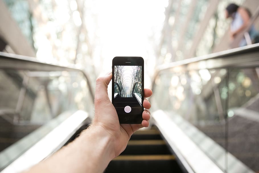 Photography on an escalator with mobile phone held in left hand HD wallpaper