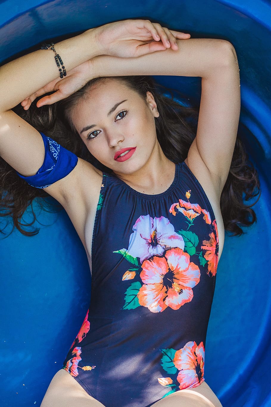 Photo of Woman in Blue Floral One-piece Swimsuit Lying Down With Hands over Head