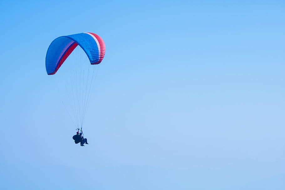 person on parachute under blue sky during daytime, leisure activities