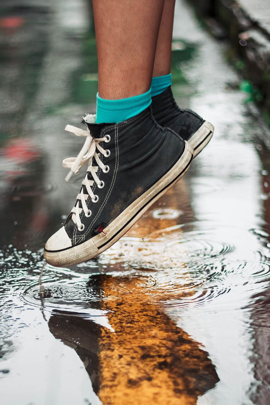 person wearing black high-top sneakers on wet floor, footwear