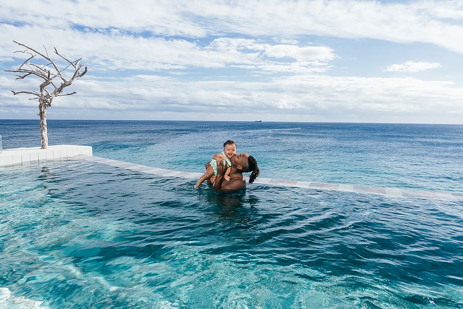 man carrying baby while standing on infinity pool, water, sea HD wallpaper